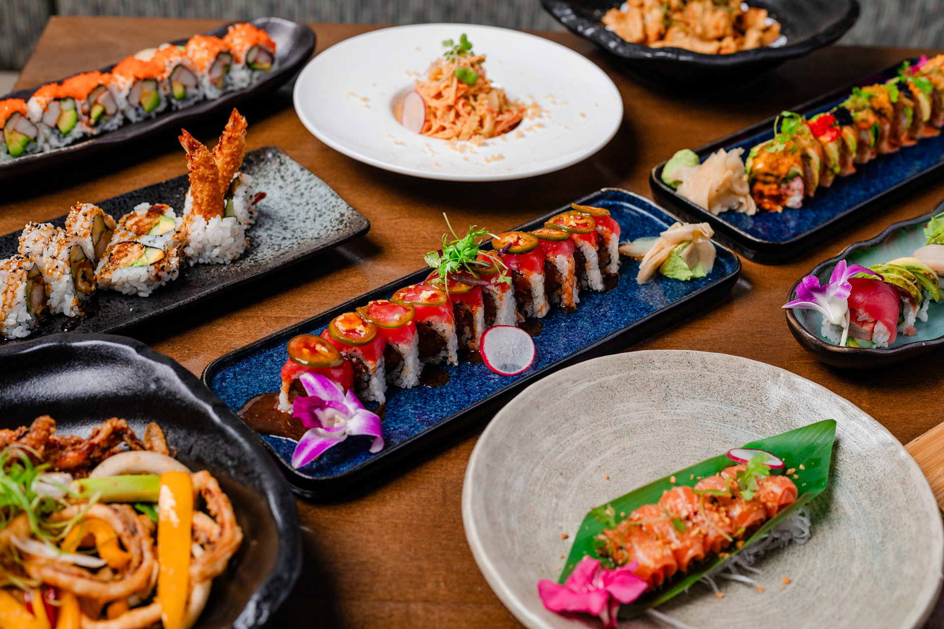 A table of colorful sushi rolls, sashimi, noodles and plated Japanese dishes